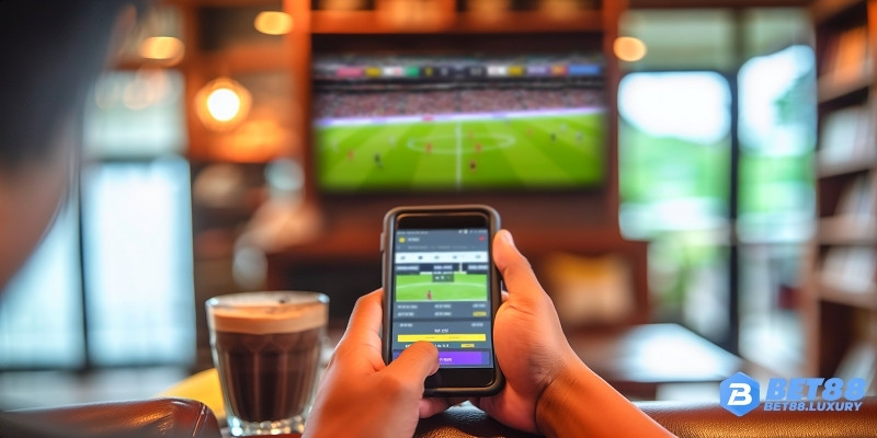 Người dùng Bet88 đặt cược bằng điện thoại tại quán cà phê